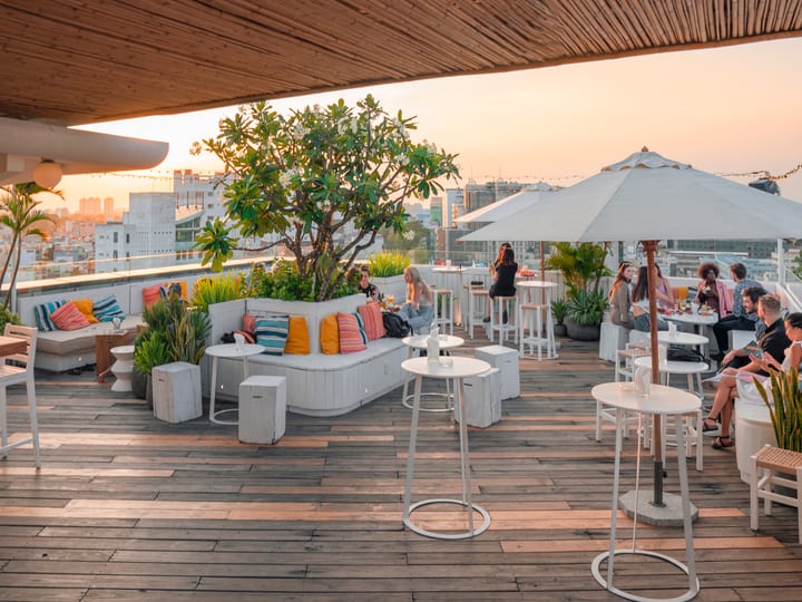 Banana Mama rooftop terrace with guests, skyline, and sunset light